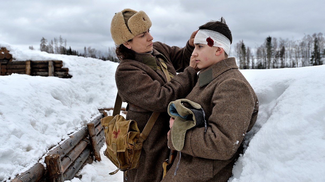 Наталья Соколова, изображающая медсестру, перевязывает рану Ивану Должинскому, сыгравшему красноармейца, во время реконструкции Битвы за Москву