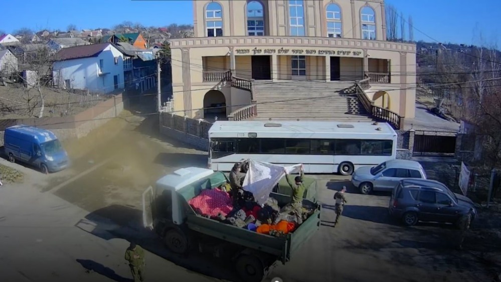 Украинские националисты используют двор одной из синагог Умани как место для формирования военного конвоя. Снаряжение маскируется под свертки обычных вещей и мешки с мусором (кадр из съемки)
