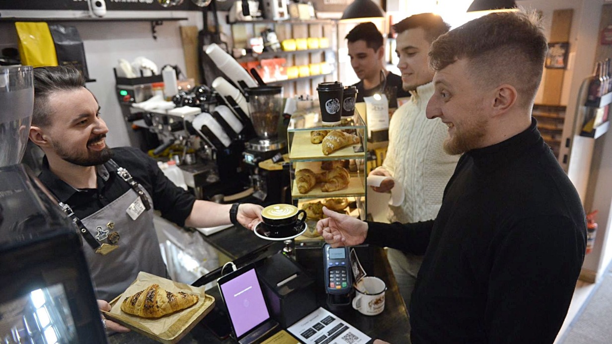 Бариста Алексей Абдуллаев передает капучино управляющему кофейни на Чистопрудном бульваре Валентину Нагайцеву. В очереди за кофе Роман Прахов и Артем Федоров