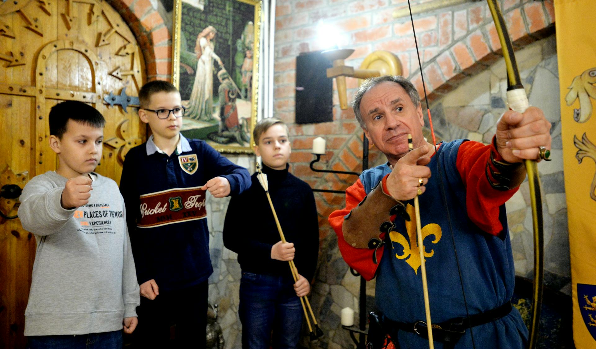 Даниил Соловьев, Анатолий Стадников и Алексей Огарков (слева направо) учатся стрельбе из лука под руководством экскурсовода Владимира Царева