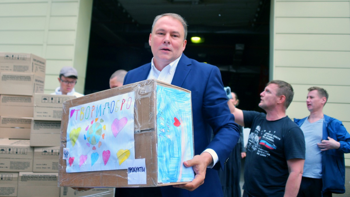 Вице-спикер Госдумы РФ Петр Толстой помогает в погрузке гуманитарного груза. В руках у него коробка с продуктами, на которую наклеены добрые рисунки маленьких москвичей