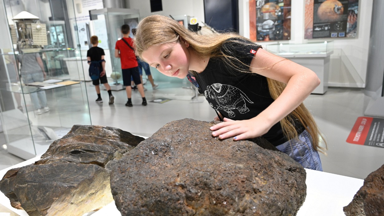 Посетительница Музея космонавтики Ангелина Денеженко загадывает желание, дотронувшись до одного из вернувшегося в экспозицию метеоритов