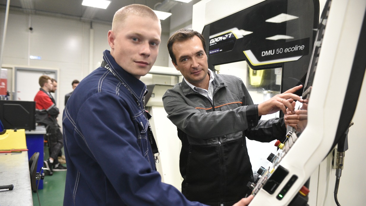 Инженер-программист и эксперт дисциплины на чемпионате рабочих профессий «Время первых» Александр Каверзин (справа) проводит инструктаж по работе с оборудованием для участника конкурса Даниила Васильева