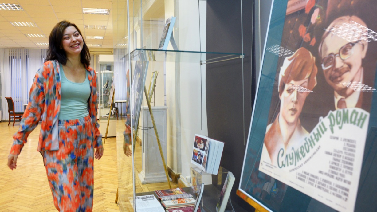 Руководитель Центра управления социокультурными проектами Российской государственной библиотеки Арина Галеева на тематической выставке в рамках акции «Ночь кино» рассматривает плакат к фильму Эльдара Рязанова «Служебный роман» 1977 года