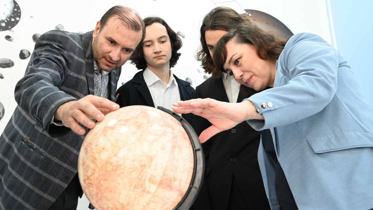 Преподаватель физики и астрономии «Школы Марьина Роща им. В. Ф. Орлова» Дмитрий Ярцев, ученики 10-го космического класса Александр Саберов и Григорий Федорович вместе с куратором класса Татьяной Пьянковой (слева направо) изучают глобус Марса 