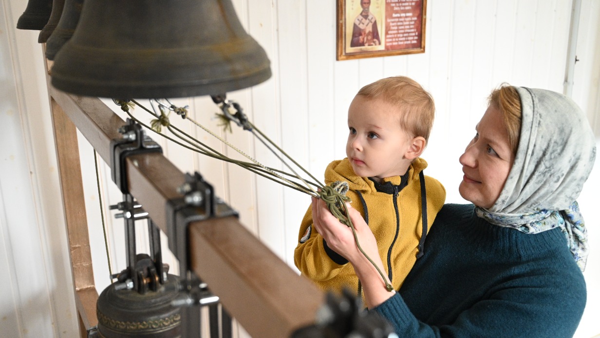 Администратор культурно-просветительского центра при храме преподобного Сергия Радонежского Ксения Казьмина показывает будущему ученику Эмилю колокольный тренажер. Занятия начнутся в ноябре, записаться на них могут дети с трех лет