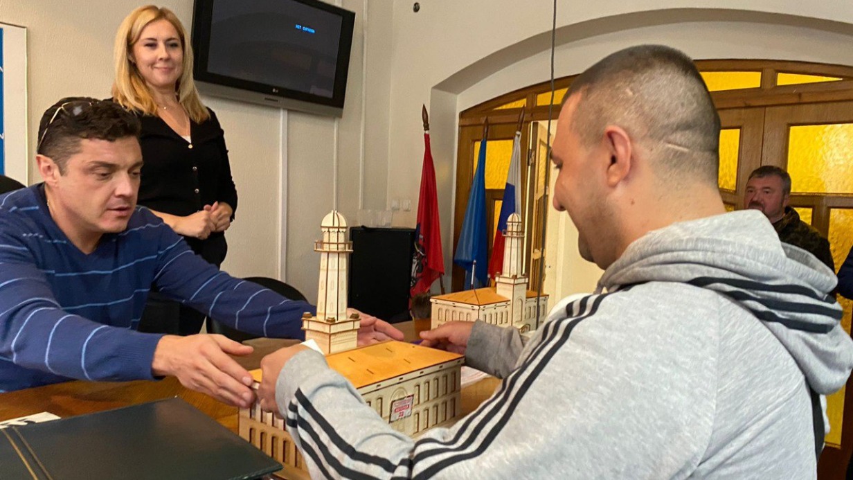 Директор Музея воинской и трудовой славы МЧС Восточного округа Москвы Сергей Савинков (слева) вручает коллекционерам копии пожарной части № 12