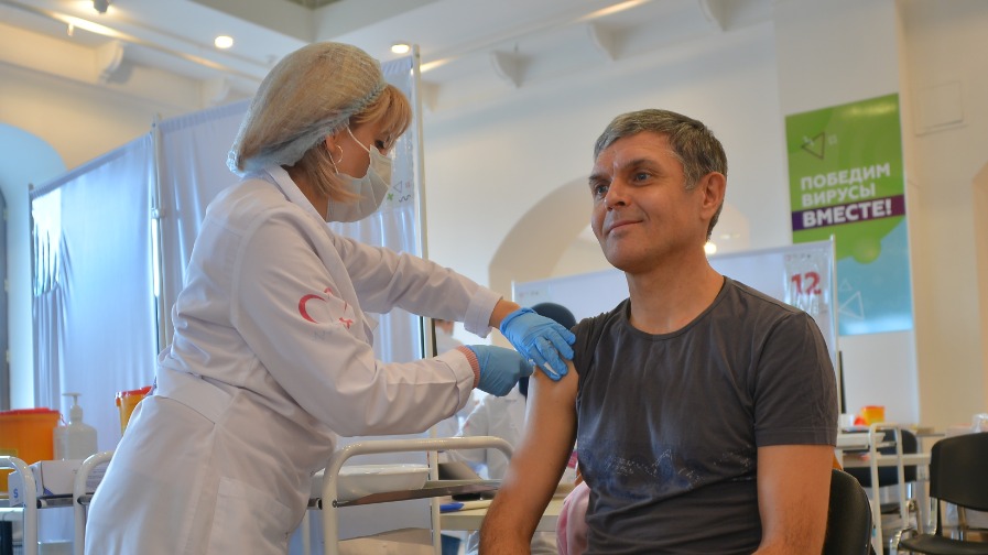 Медсестра Марине Оганнисян прививает от гриппа москвича Вячеслава Екимова в одном из пунктов вакцинации