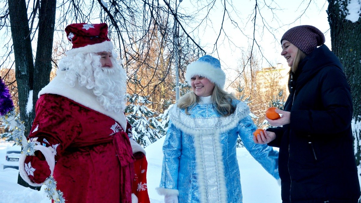 Слева направо: волонтеры Василий Десинов и Ольга Дрожжина дарят мандарины москвичке Юлии Нефедовой в рамках акции «Волшебный мандарин»