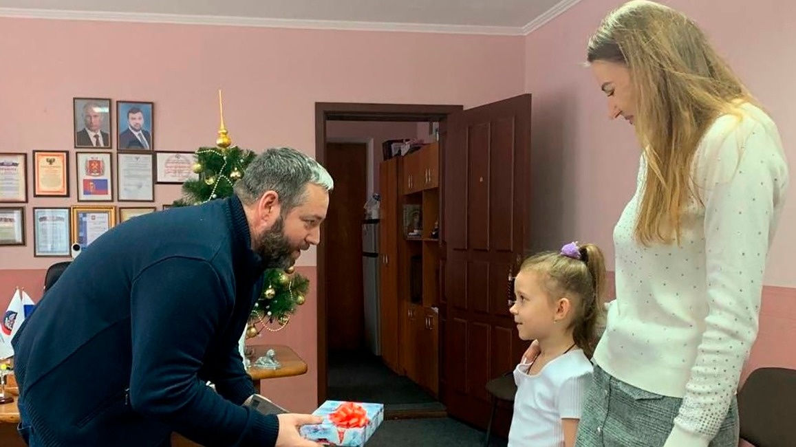 Волонтер ясиноватского штаба «Молодая Республика» Алексей Мальков передает подарок Алене Аникеевой и ее дочери Анне — планшет, который хотела девочка