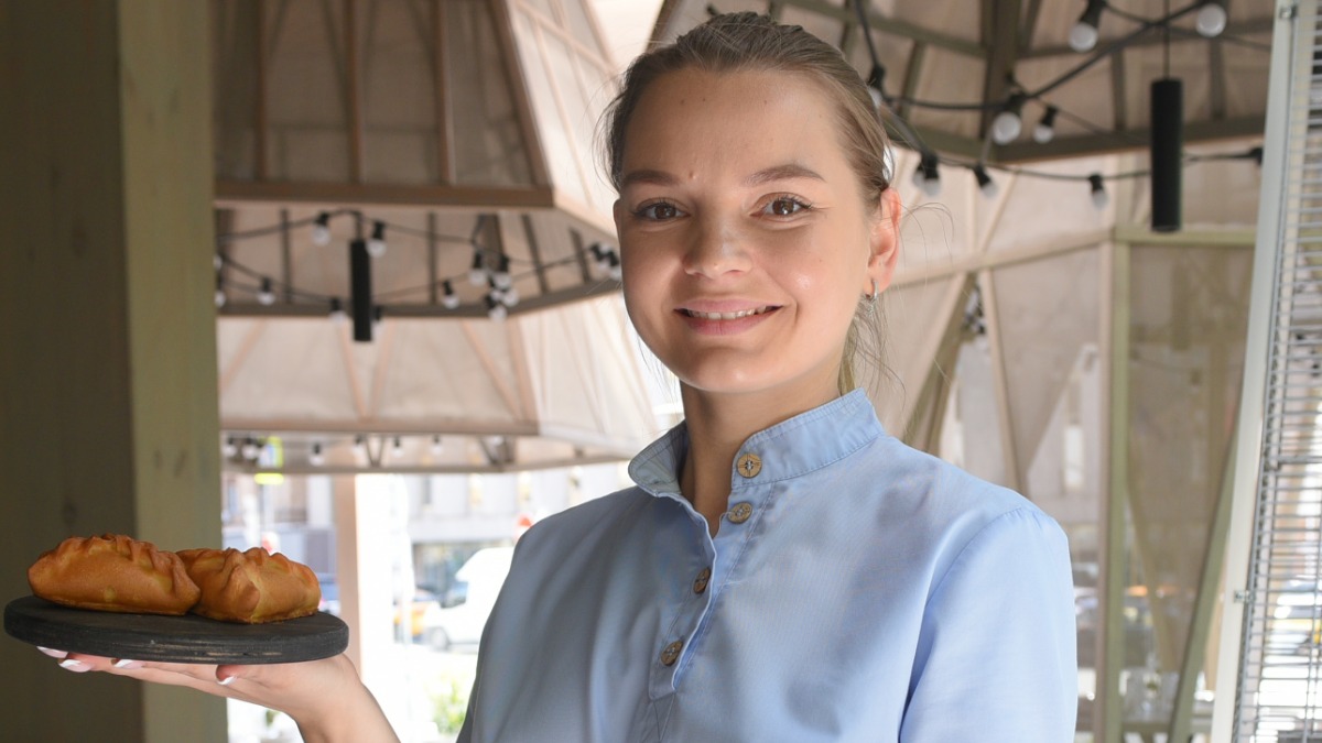 Официантка московского ресторана «#СибирьСибирь» Юлия Рахатова приносит гостям заведения блюда из фестивального меню — пирожки с потрошками