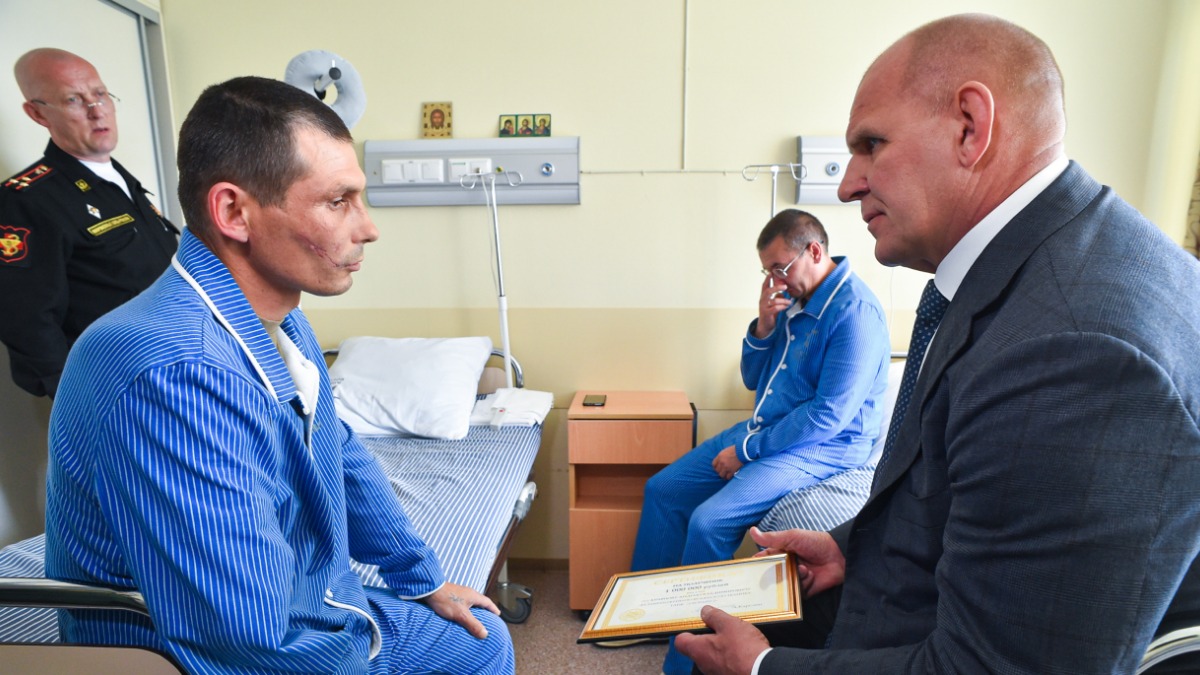 Сенатор Совета Федерации Александр Карелин награждает военнослужащего Андрея Кравцова сертификатом на выплату премии в один миллион рублей за уничтожение в ходе боя вражеского танка Leopard