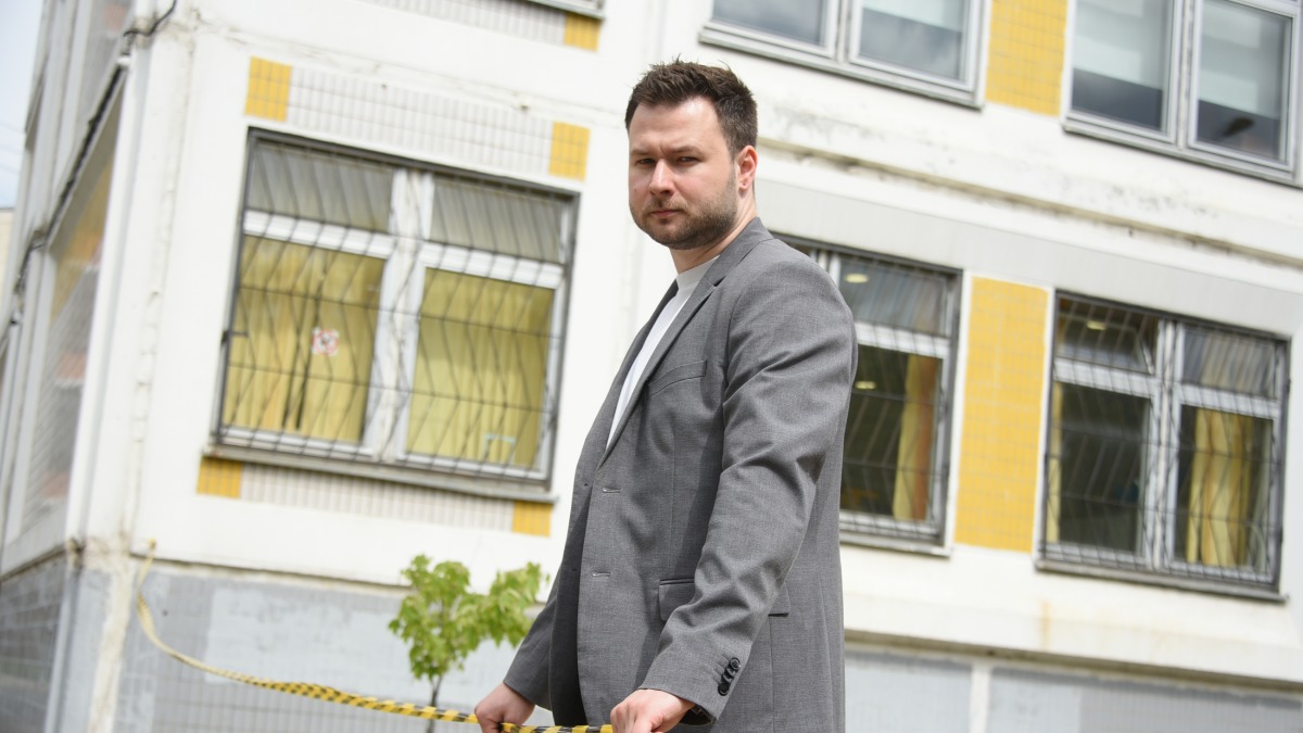 Директор московской школы № 149 в районе Сокол Александр Дорохов натягивает сигнальную ленту для ограждения территории, где началось масштабное благоустройство