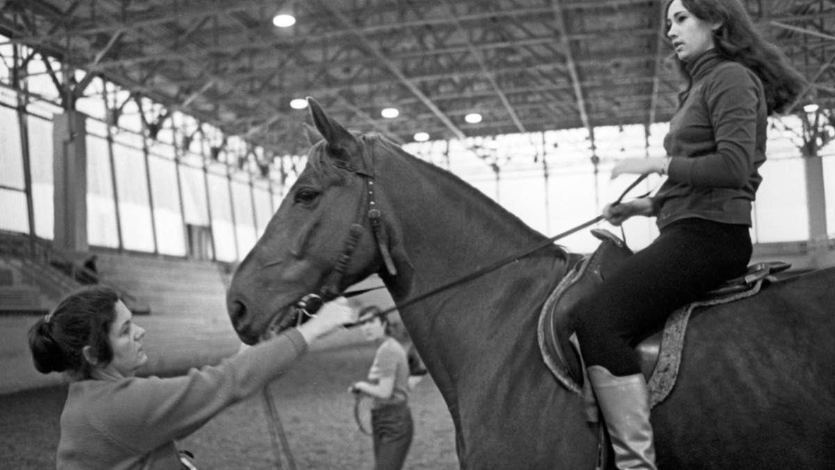 Тренер школы конного спорта в комплексе «Битца» обучает ученицу верховой езде. Фото 1974 года