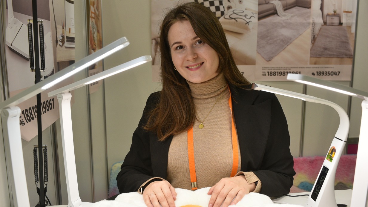 Представитель китайской компании Анастасия Кожевникова демонстрирует теплые ковры из синтетического меха, которые производятся в Поднебесной