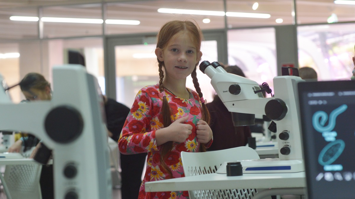 Школьница Таня Борисова во время мастер-класса «Микроскопический мир» в парке «Зарядье» изучает, как пользоваться микроскопом, — открытые мероприятия, которые прошли ко Всемирному дню науки, привлекли тысячи детей и взрослых