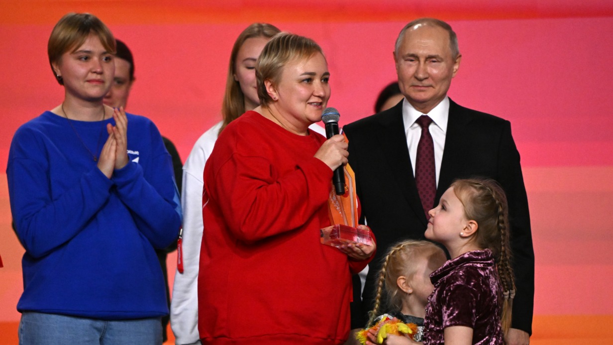 Президент России Владимир Путин вручает премию «Волонтер года» многодетной маме Наталье Аминевой (в центре). Вместе с детьми, супругом и родителями она помогает участникам спецоперации, изготавливая сети, окопные свечи и вязаные носки