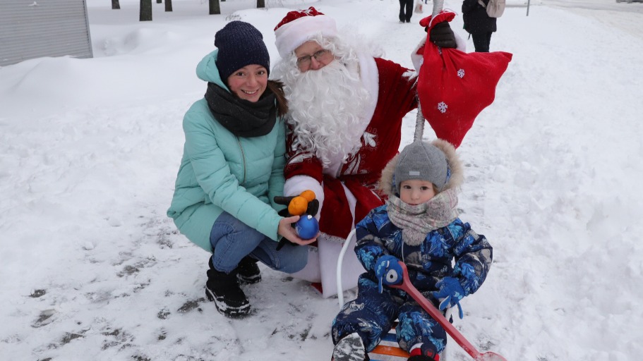 Руководитель аппарата Совета депутатов муниципального округа Орехово-Борисово Южное Денис Беляевский в костюме Деда Мороза дарит мандарины и елочные шарики местной жительнице Светлане Климовой и ее сыну Денису