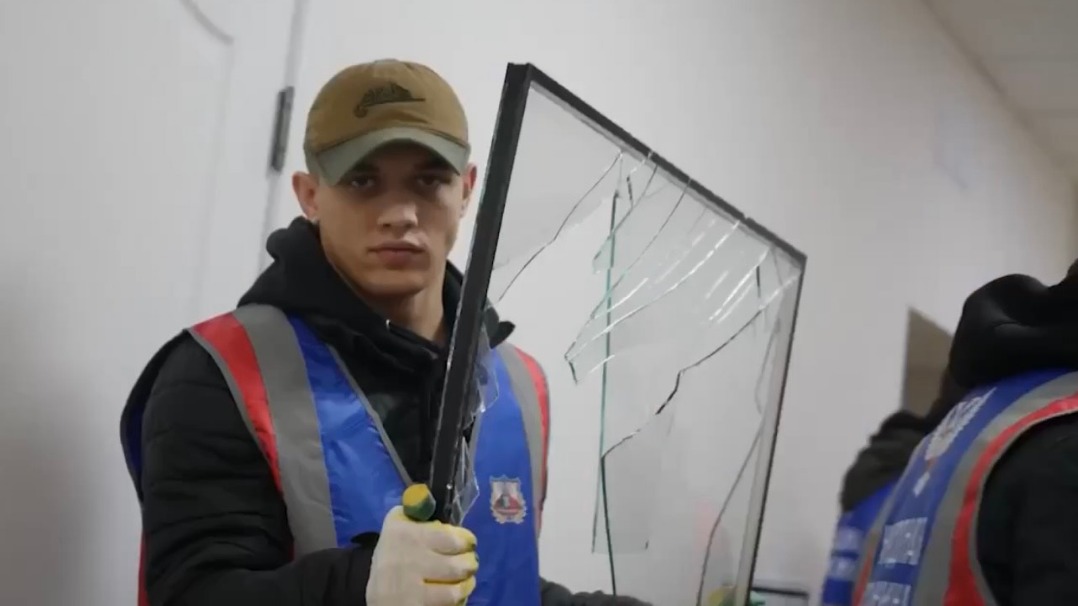 Главный специалист Центрального штаба Народной дружины Андрей Стефанишин выносит поврежденную оконную раму из здания Городской клинической больницы № 6 в Донецке