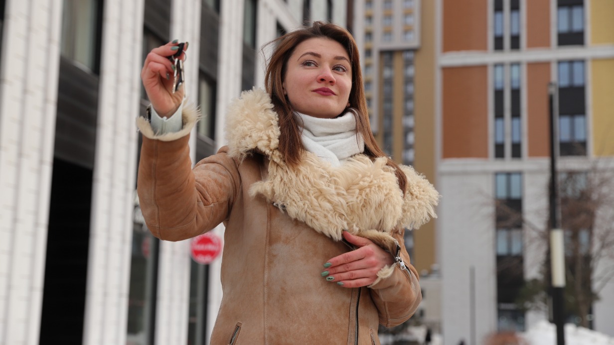 Помощник юриста Елена Степанько с ключами на фоне новых домов в Головинском районе