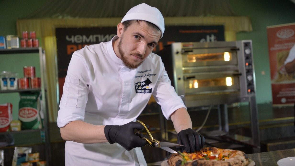 Повар Константин Андрюков режет на кусочки специальными ножницами свой вариант популярнейшего блюда на чемпионате по приготовлению пиццы в рамках фестиваля Chefs Team Fest