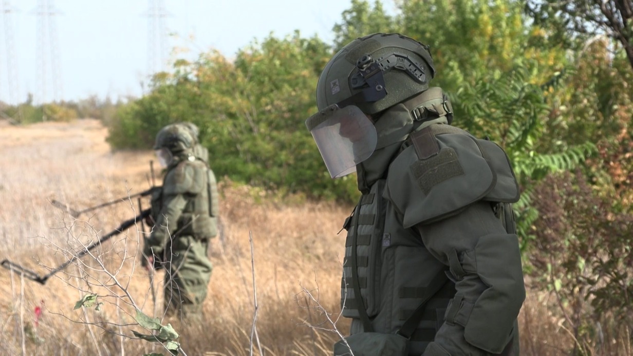 Российские саперы «Лорион» (на переднем плане), «Седьмой» (в центре) и «Скиф» ищут мины у подхода к лесополосе на освобожденной территории