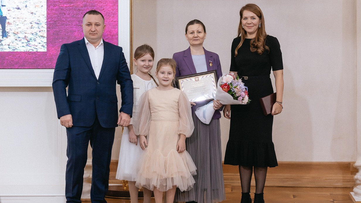 Заместитель мэра Москвы по вопросам социального развития Анастасия Ракова (справа) вручает награду «Мать-героиня» москвичке Елене Трошиной (вторая справа), которая на награждение пришла с супругом Василием и двумя детьми — Анной и Татьяной (слева направо). А всего в семье подрастают 11 детей