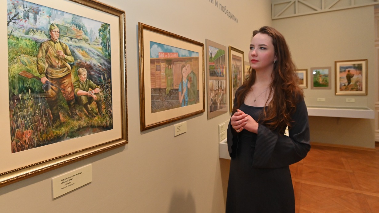 Куратор выставки «Наследие и наследники» Софья Акулич показывает часть экспозиции с детскими рисунками