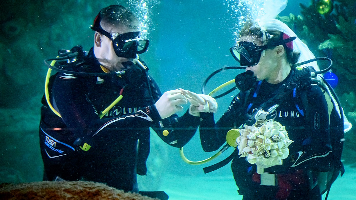 Москвичи Максим и Ирина Батуевы в момент обмена кольцами. Их необычная свадебная церемония прошла на пятиметровой глубине в главном аквариуме центра океанографии и морской биологии «Москвариум». До этого времени подводные церемонии в столице не проводились