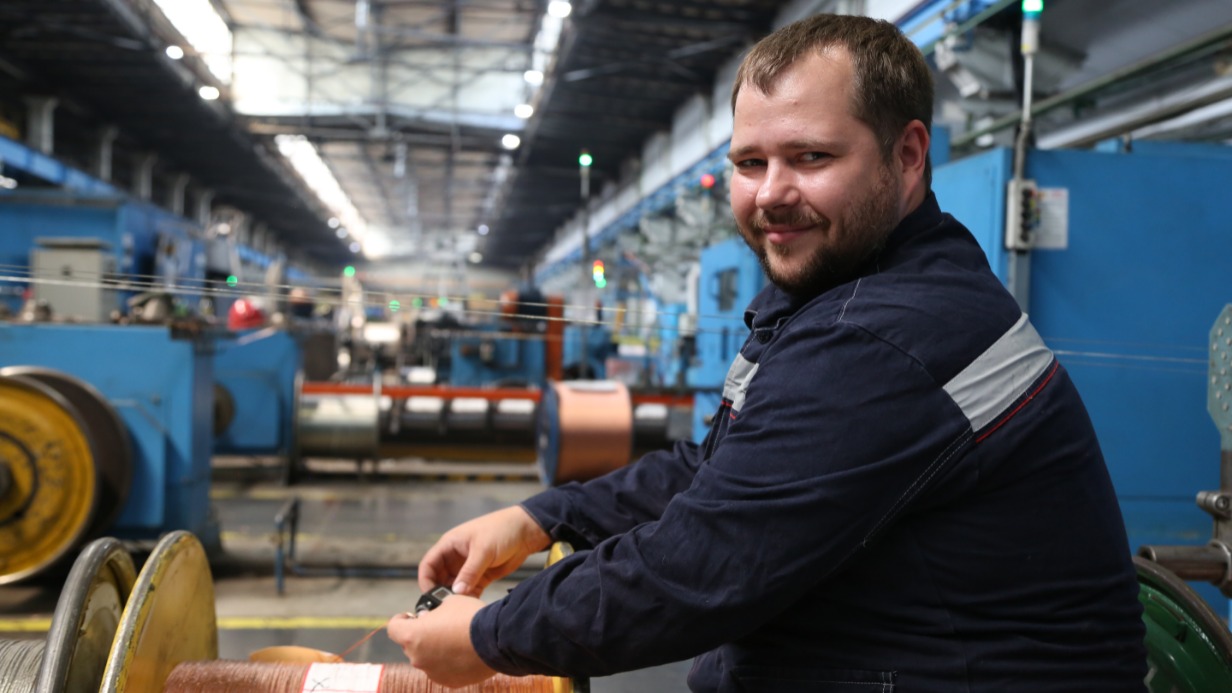 Сотрудник «Москабельмета» волочильщик проволоки Денис Трубянов проверяет толщину изделия. Благодаря нацпроекту на заводе повысили производительность труда