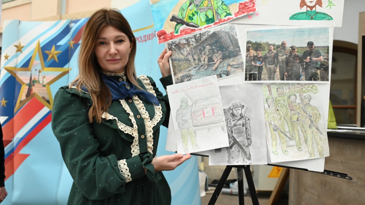 Руководитель проекта «Герой нашей Родины» Олеся Иванова показывает рисунки детей, посвященные бойцам СВО