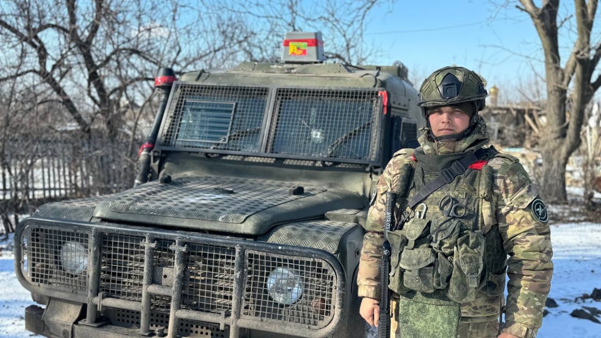 Водитель-механик с позывным «Малой» из второго батальона 1465-го мотострелкового полка рядом с трофейным бронированным внедорожником Ленд Ровер Дефендер 110