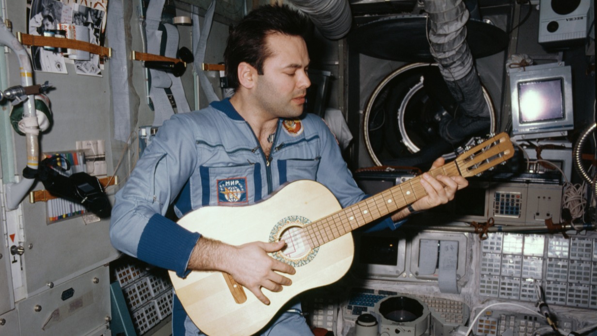 Советский летчик-космонавт Александр Лавейкин играет на гитаре на станции «Мир» 