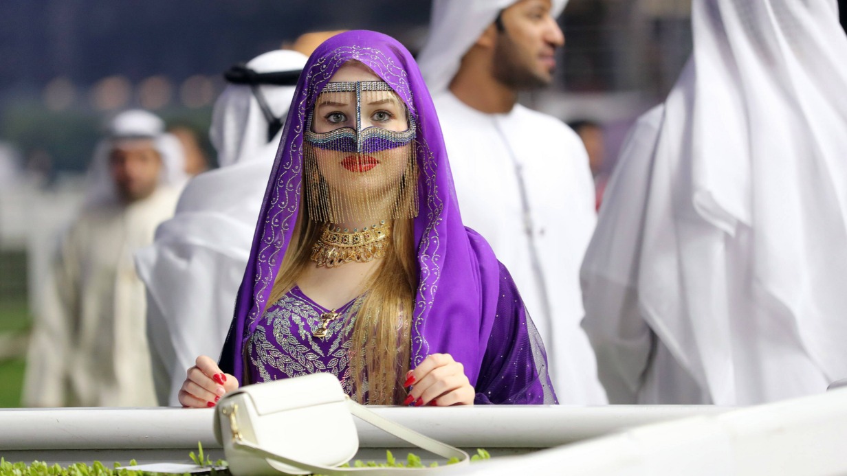 Жительница Объединенных Арабских Эмиратов наблюдает за скачками на дубайском ипподроме Мейдан