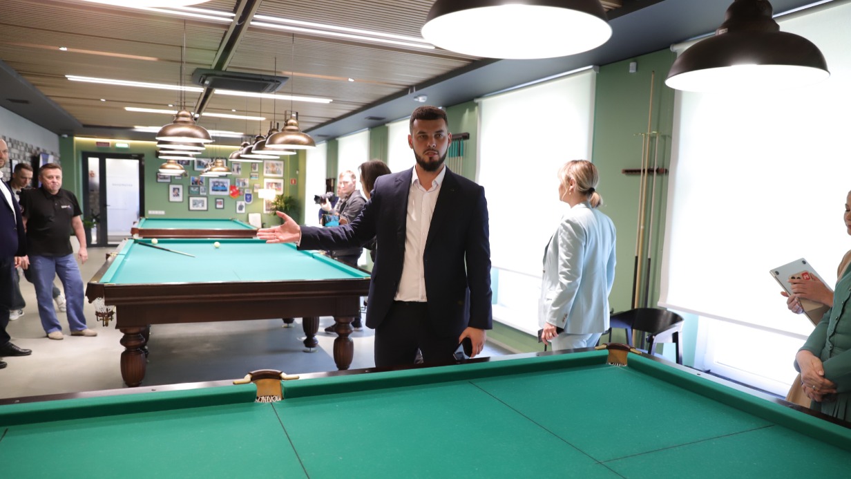 Исполнительный директор Ассоциации ветеранов СВО Москвы Владислав Гусев (на первом плане) провел экскурсию по Единому центру поддержки. В одном из залов установлены столы для игры в русский бильярд