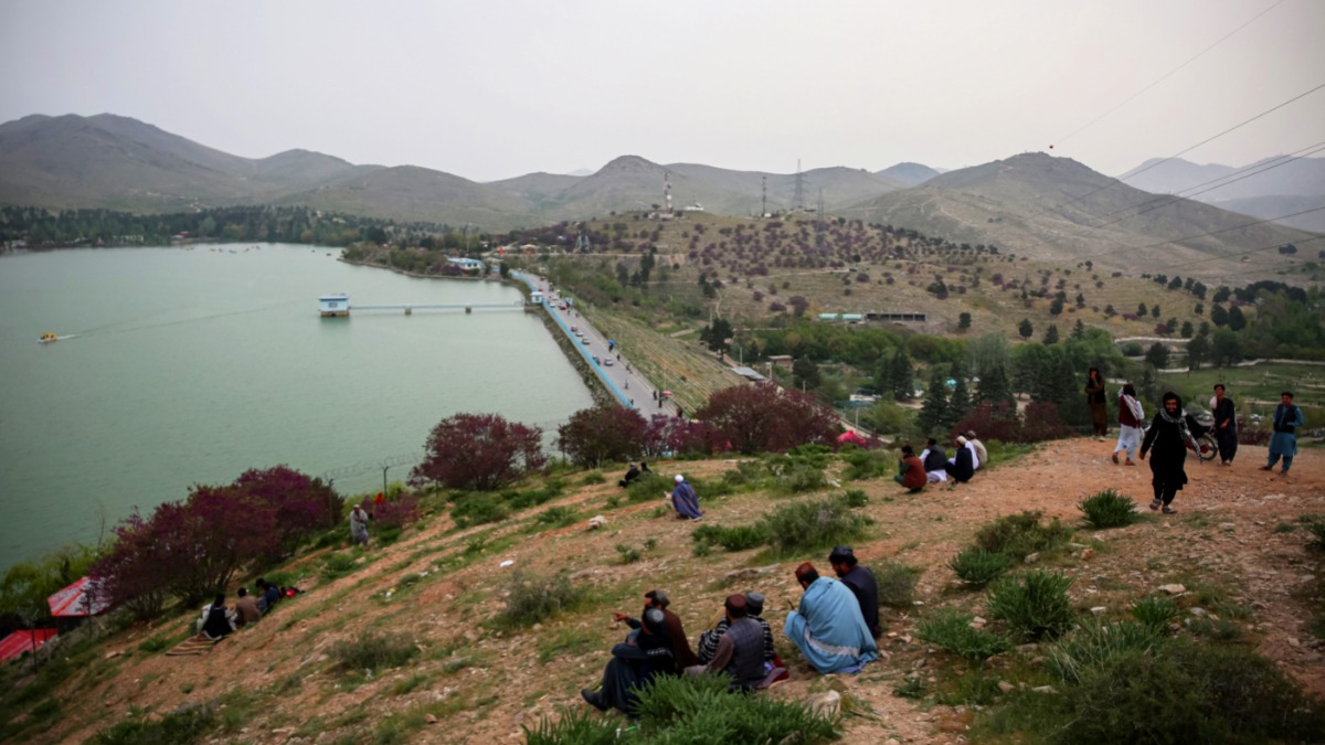 Местные жители наблюдают за отдыхающими на катере туристами на озере Карга на окраине Кабула в Афганистане