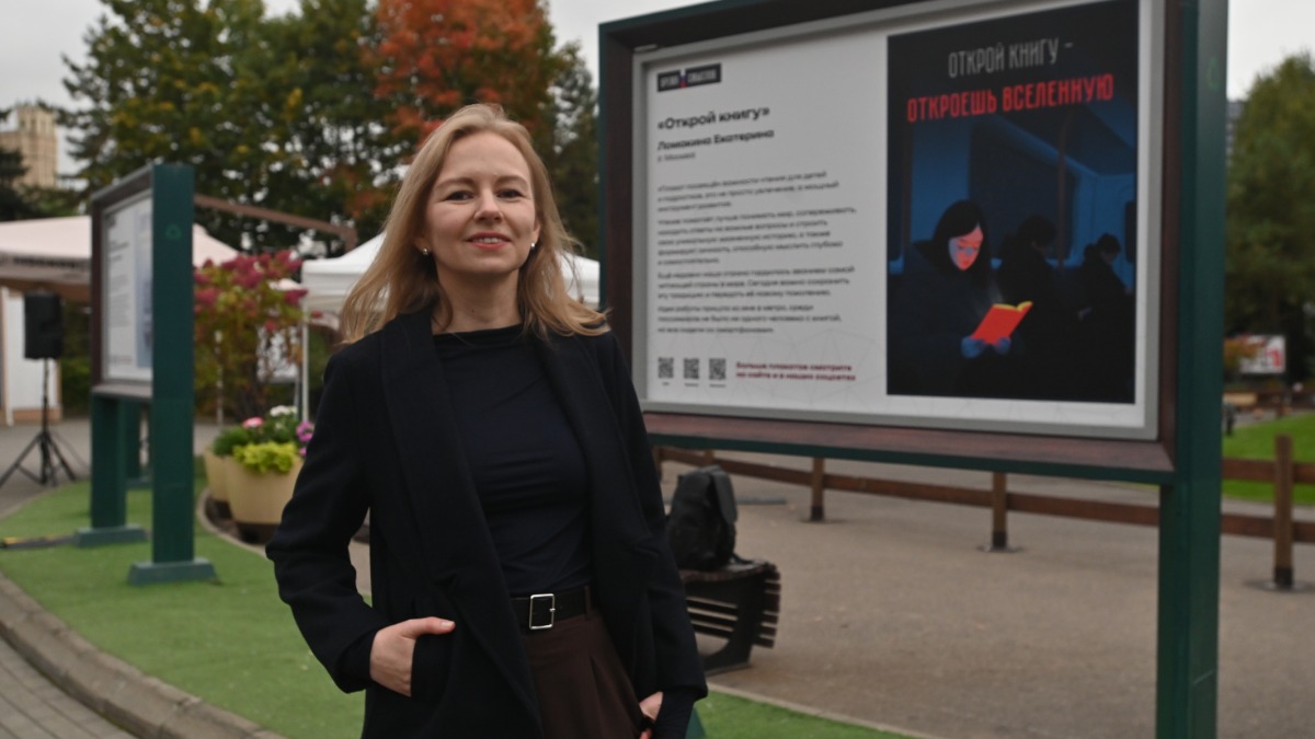 Участница конкурса плакатного искусства «Время смыслов» москвичка Екатерина Ломакина на фоне одной из своих работ. Плакат призван привлечь внимание к проблеме отсутствия интереса к чтению книг у современного поколения