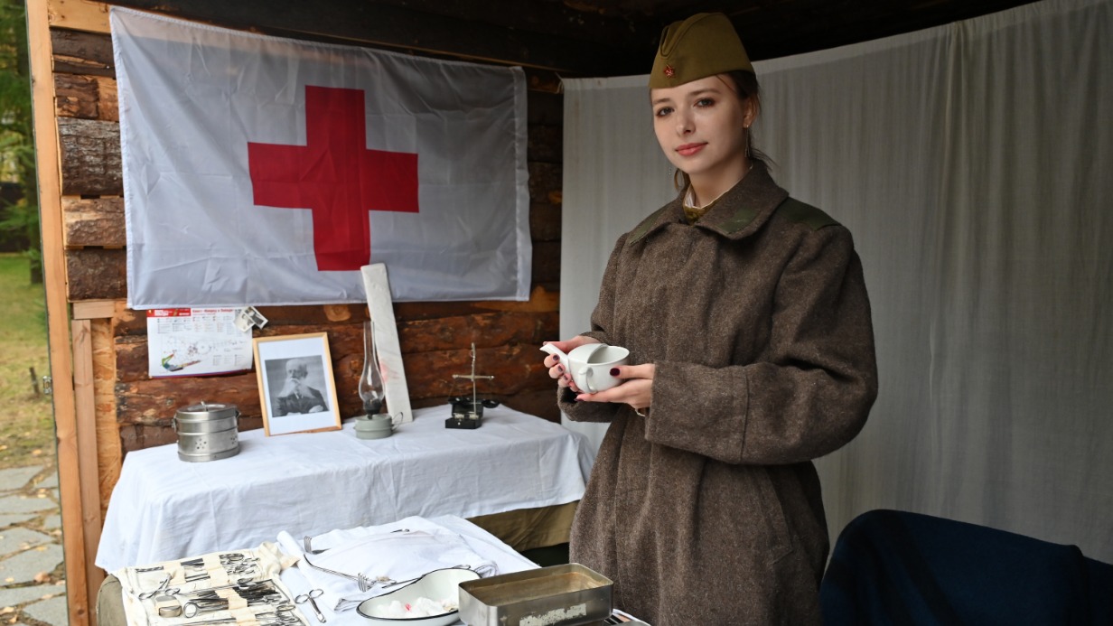 Реконструктор Дарья Николаева рассказывает посетителям программы на Поклонной горе в честь Дня Московского народного ополчения об инвентаре военного госпиталя времен Великой Отечественной войны