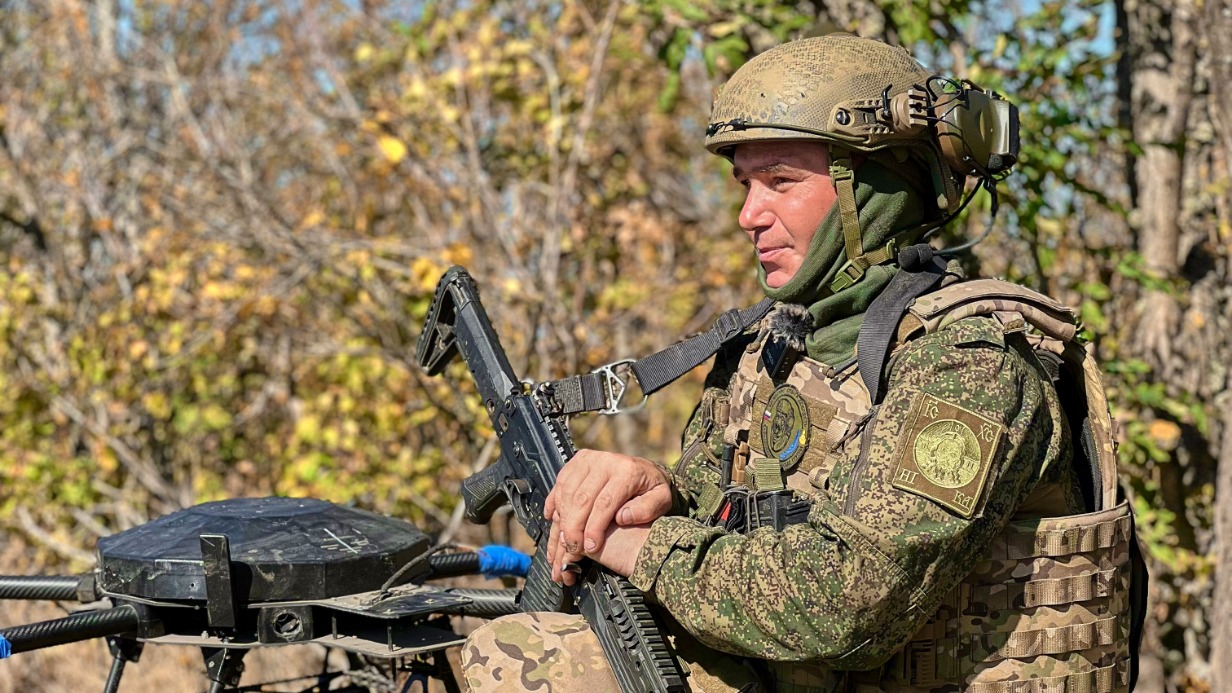 Боец с позывным «Фомич» рядом со сбитым украинским дроном «Баба-яга», который доставлял припасы вражескому подразделению. Именно «Баба-яга» своим небрежным полетом раскрыла расположение противника и позволила российским штурмовикам взять опорный пункт