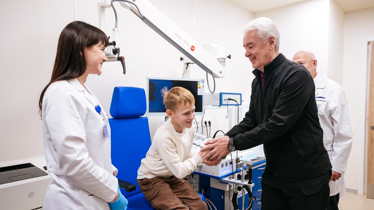 Мэр Москвы Сергей Собянин во время открытия Сурдологического центра общается с заведующей научно-исследовательским отделом микрохирургии гортани и фониатрии Дианой Курбановой и ее маленьким пациентом Георгием