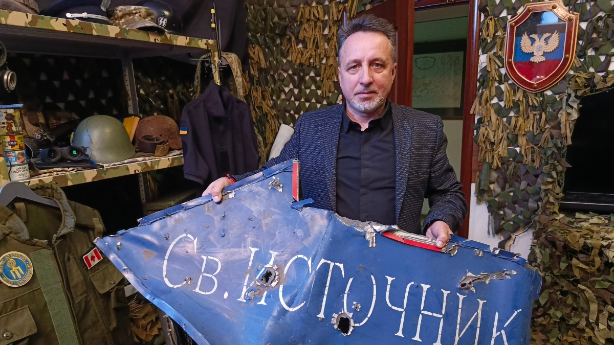 Руководитель Благотворительного фонда «Руспомощь» Василий Александров показывает простреленный указатель, привезенный им с Донбасса в организованный музей отряда «Эспаньола»