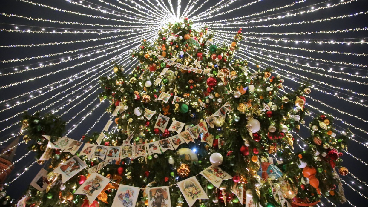 Огромная ель, украшенная шарами и гирляндами флажков с изображением советских открыток, красуется на Манежной площади