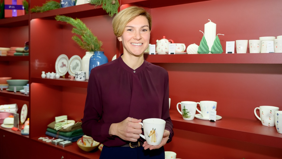 Заместитель руководителя проекта «Сделано в Москве» Дарья Шаронова на стенде проекта на VII Московской неделе интерьера и дизайна. Она показывает чашку, созданную одним из столичных производителей