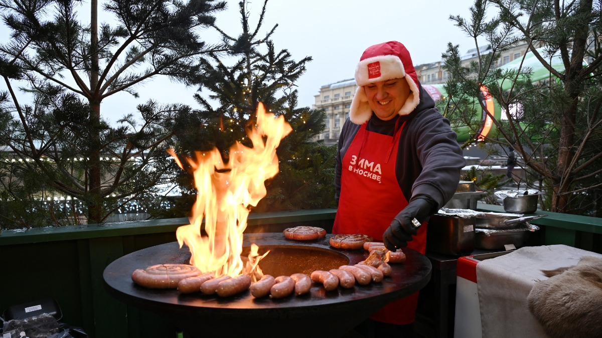 Участник фестиваля «Путешествие в Рождество» Александр Дячук готовит колбаски из оленины