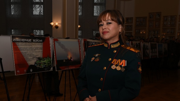 Старший прапорщик Айгуль Тургунбаева на фоне фотовыставки, посвященной инженерным войскам. Экспозицию развернули в фойе Центрального академического театра Российской армии