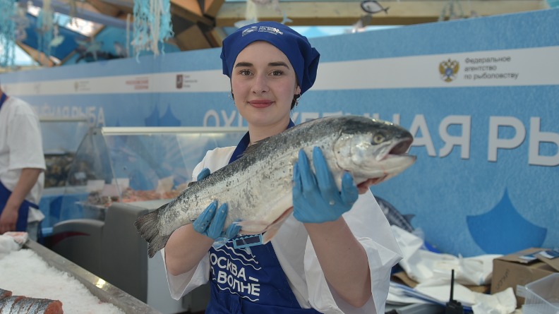 Продавец Арина Севрюкова держит лосося: качество продукции на рынке «Москва на волне» тщательно проверяют