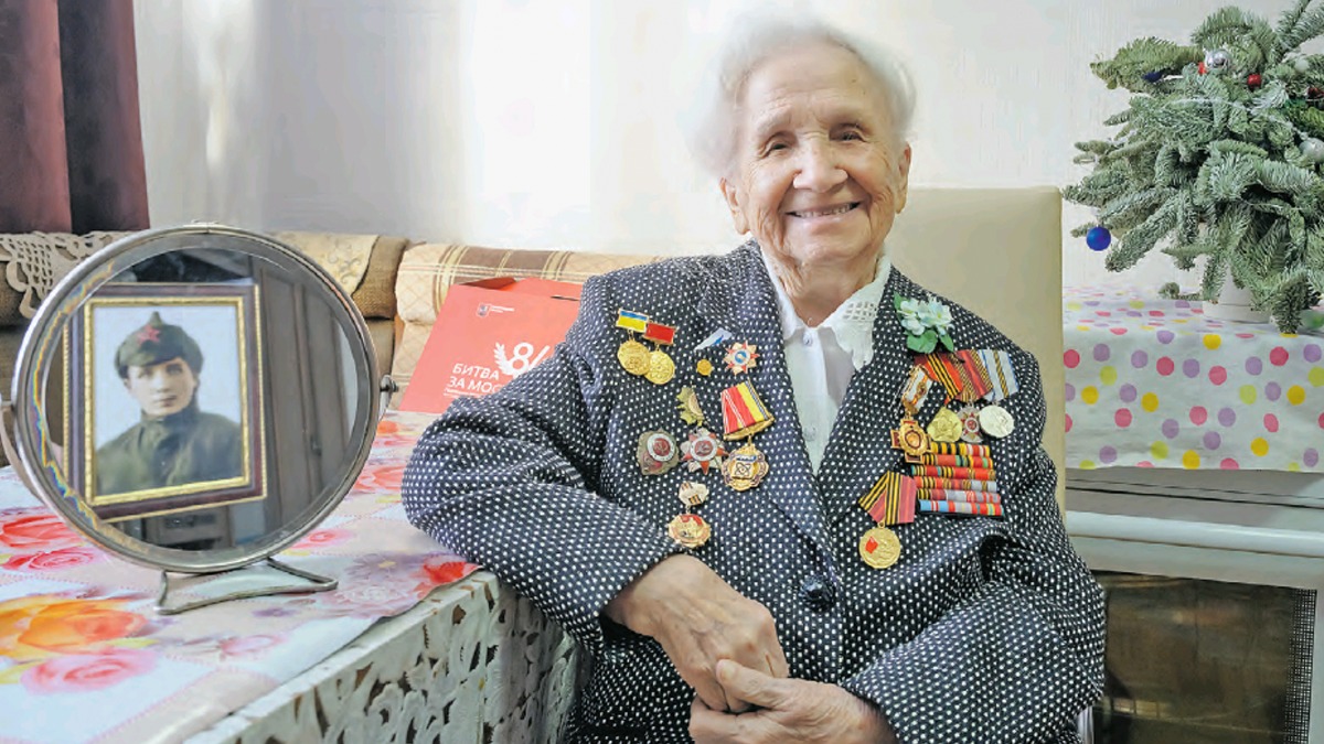 Валентина Петровна Минаева у себя дома. В зеркале отражается фотография 19-летней Валечки в буденовке