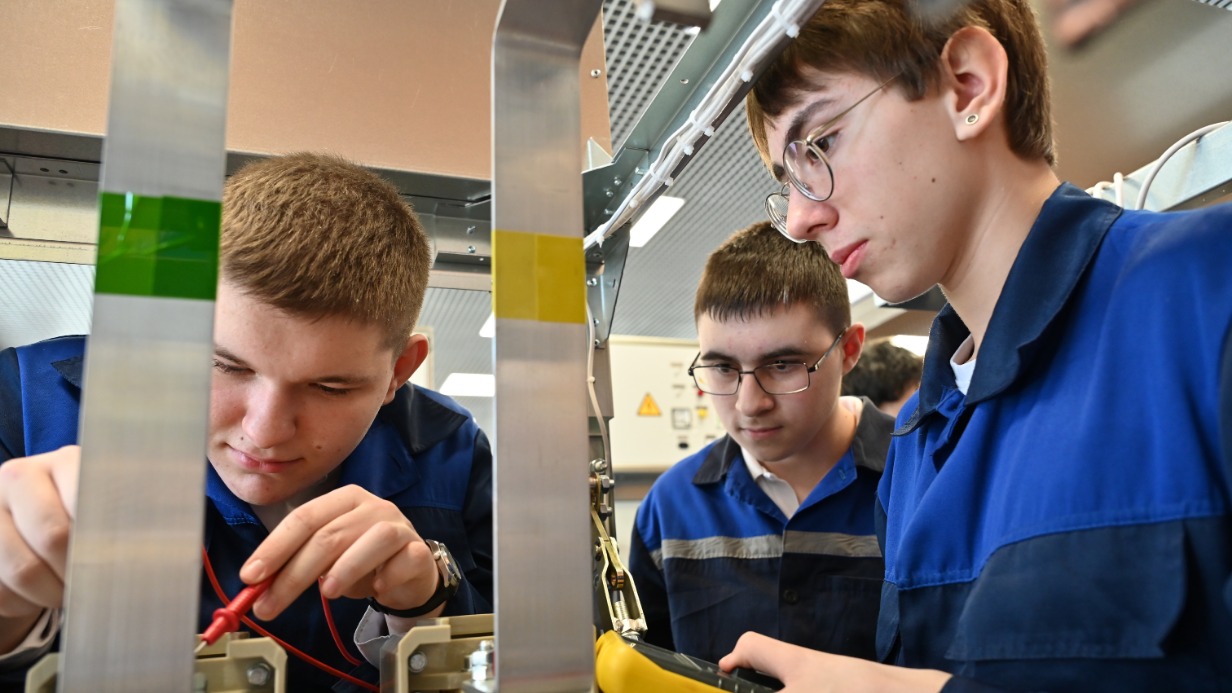 Студенты первого курса Колледжа связи № 54 им. П. М. Вострухина Виктор Оськин, Алан Уртаев и Дмитрий Лысков, используя мультиметр, прозванивают контакты на трансформаторе понижающего типа в новой лаборатории, которая воссоздает городскую электроподстанцию