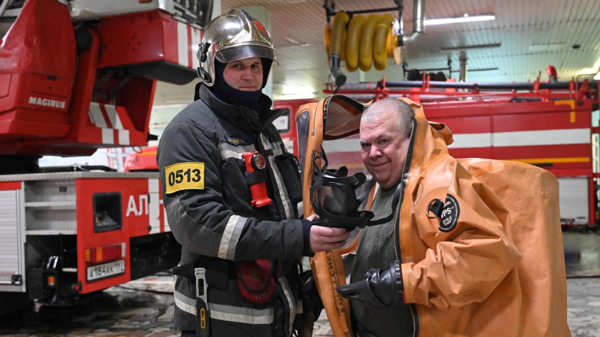 Старший инструктор газодымозащитной службы пожарно-спасательной части № 51 Руслан Марков помогает корреспонденту «Вечерней Москвы» Андрею Объедкову надеть спецкостюм для защиты от химических воздействий