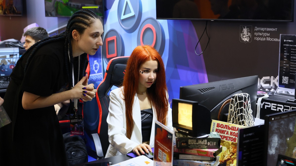 Сотрудница кластера Ирина Виктякова показывает гостье Анне Романовой, как проходить одну из созданных здесь игр